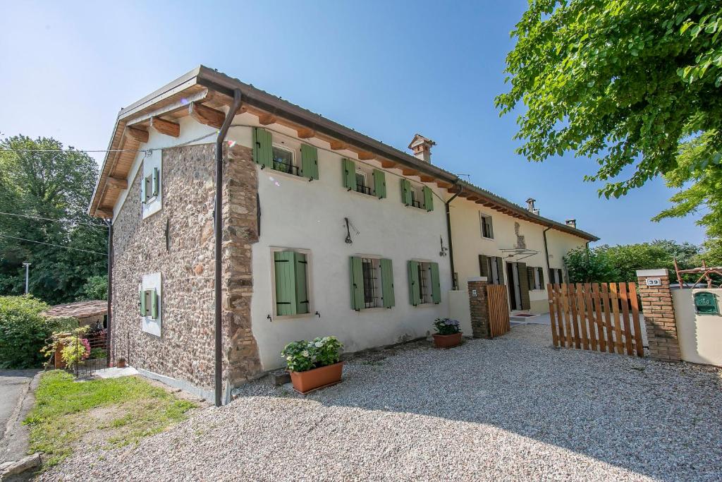 una antigua casa de piedra con ventanas con persianas verdes en Casa Mondragon In Lazise - Happy Rentals en Lazise