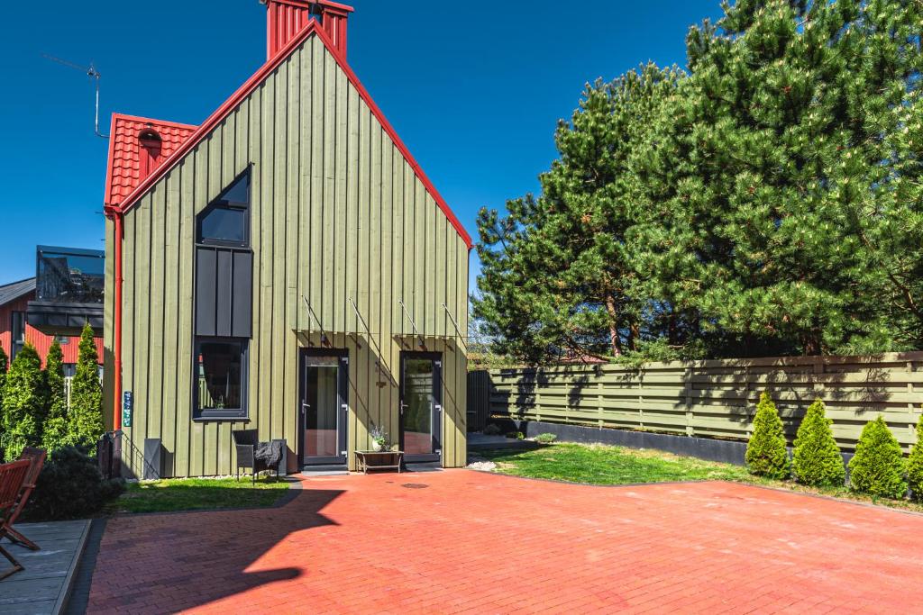 a church with a red roof and a tree at Žalia Kopa apartamentai in Palanga