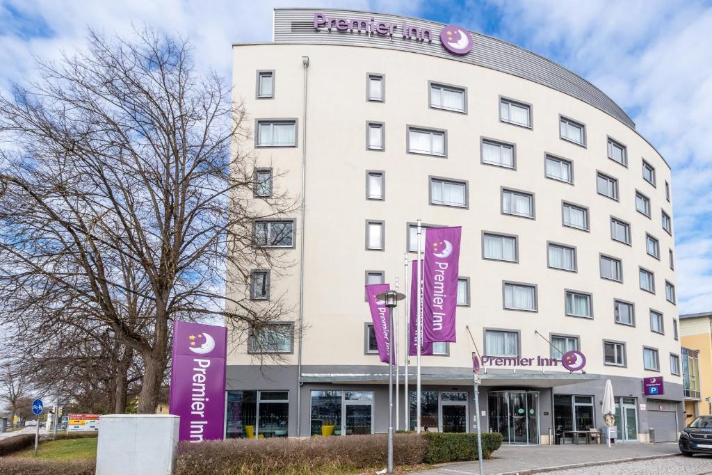 a white building with purple signs in front of it at Premier Inn München Messe in Haar