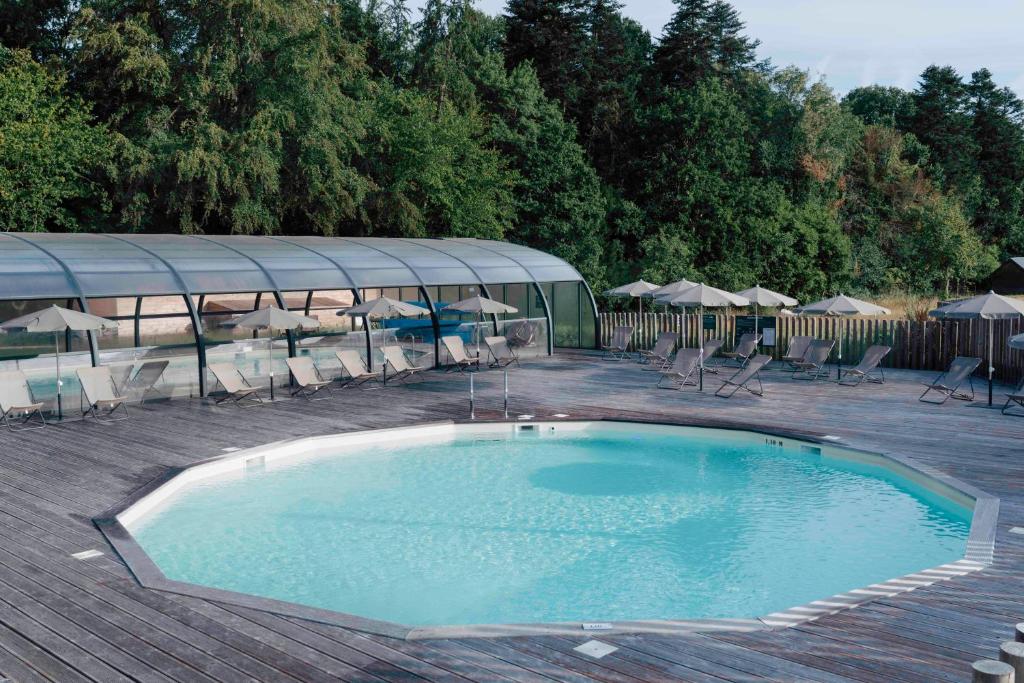 una gran piscina con sillas y sombrillas en Huttopia Calvados - Normandie, en Moyaux