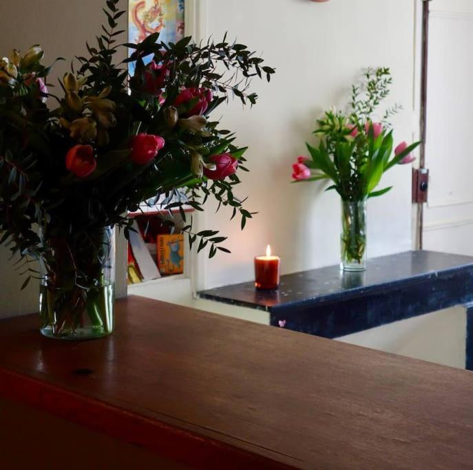 une table avec deux vases avec des fleurs et une bougie dans l'établissement Appartement Quartier Latin 4 personnes, à Paris