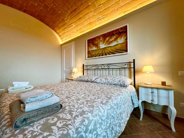 a bedroom with a bed with two night stands and a painting at Sangi Chianti Vacations in Poggibonsi