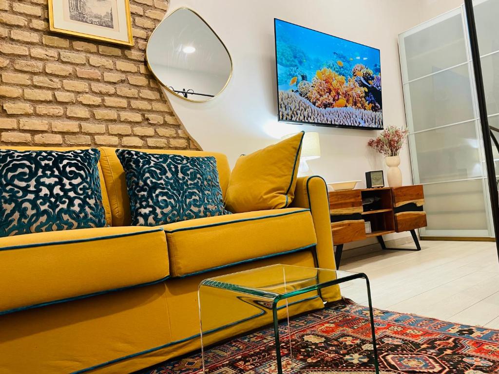 sala de estar con sofá amarillo y pared de ladrillo en Colosseum-Apartments en Roma