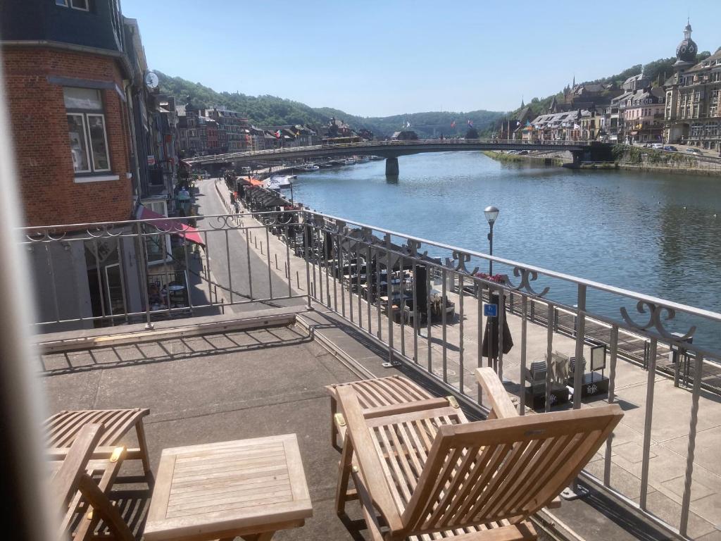 a view of a river with chairs and a bridge at Les Terrasses de Sax in Dinant