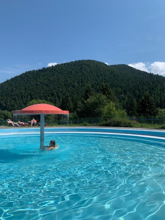 a person in a swimming pool with a red umbrella at SOMTU design apartments in Liptovský Ján