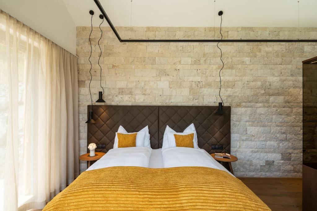 una camera con un grande letto e un muro di mattoni di steiRerBLiCke - Weingartenresidenz Guntschenberg 
