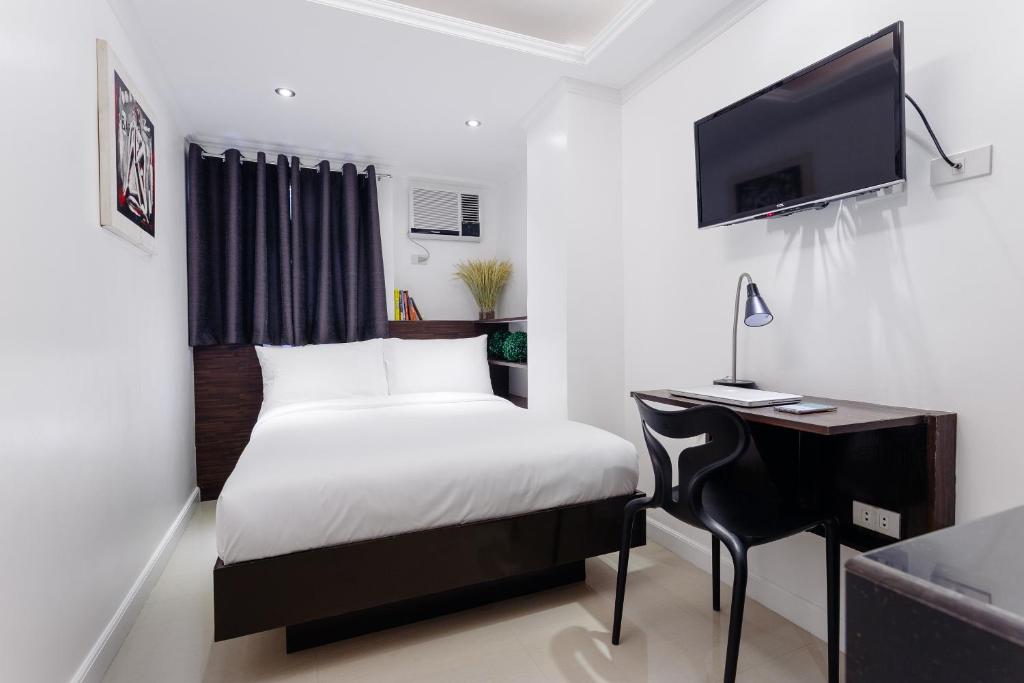 a bedroom with a bed and a desk and a tv at NEST NANO SUITES POBLACION-MAKATI in Manila
