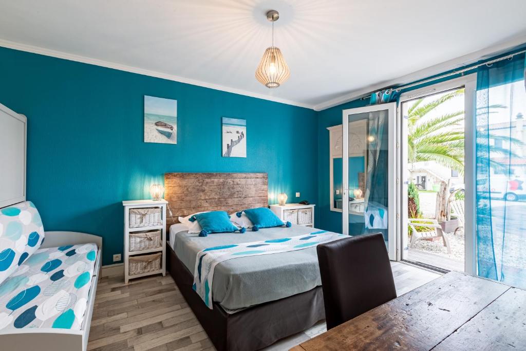 sypialnia z niebieskimi ścianami, łóżkiem i stołem w obiekcie Villa Cordouan w mieście Saint-Palais-sur-Mer