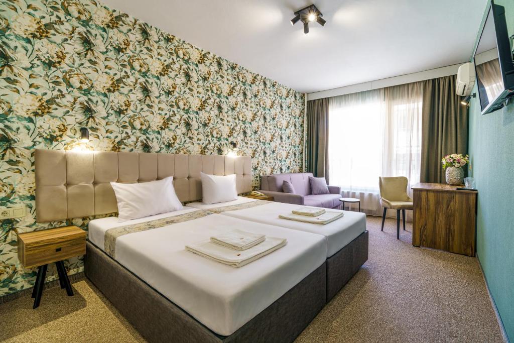 una habitación de hotel con una cama grande y una silla en Bistra & Galina Hotel, en Ruse