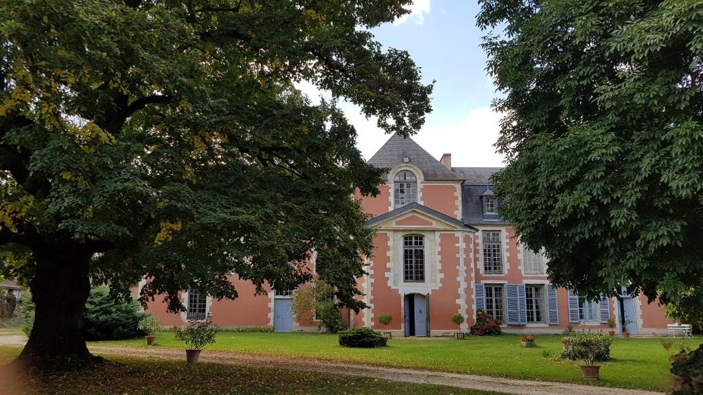 una gran casa rosa con un árbol en el primer plano en Le boudoir de Yaya en Cosne Cours sur Loire