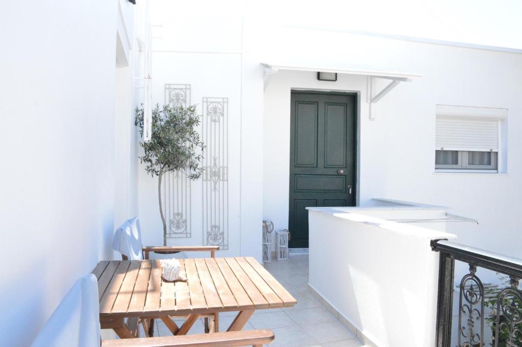 a porch with a wooden table and a black door at Cute Studio in Milos in Tripiti