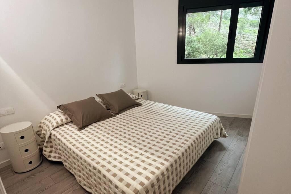 a bedroom with a bed with a checkered blanket and a window at Nuevo, espacioso y confortable con pkg y piscina in Tossa de Mar