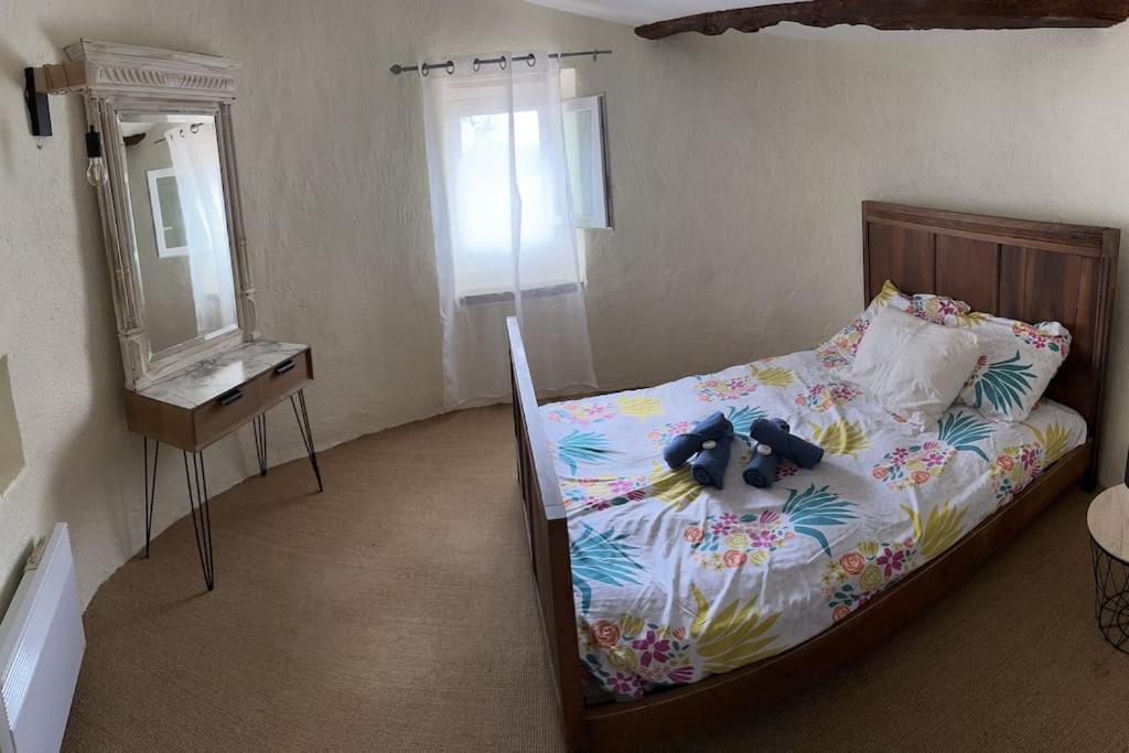 een slaapkamer met een bed, een dressoir en een spiegel bij maison à la campagne in Quinson