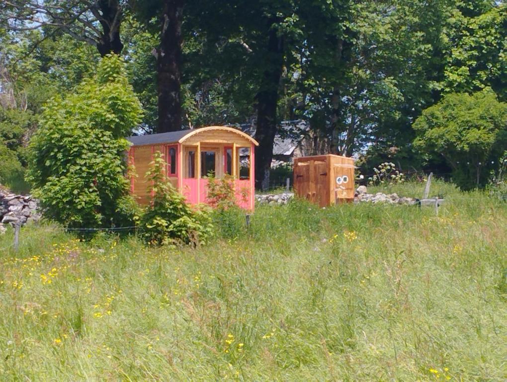 una piccola casa in mezzo a un campo di La Roulotte romantique du P'tit Buron a Saint-Saturnin