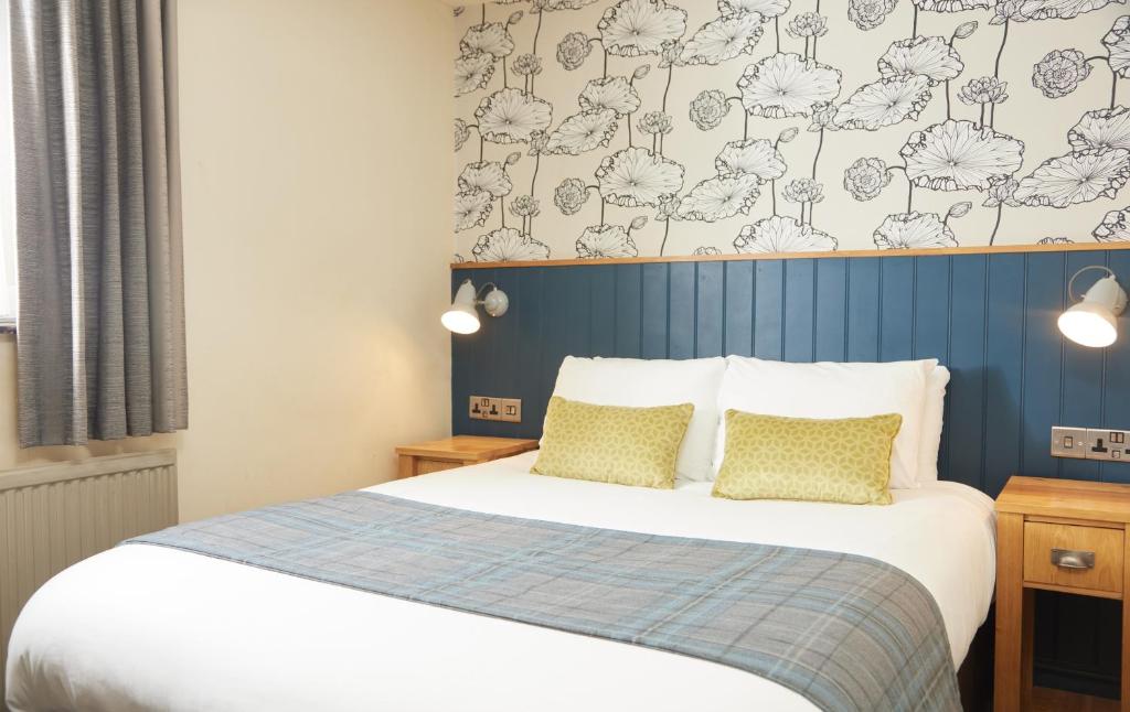 1 dormitorio con 1 cama y una pared azul y blanca en Red Lion Hotel by Greene King Inns en Banbury