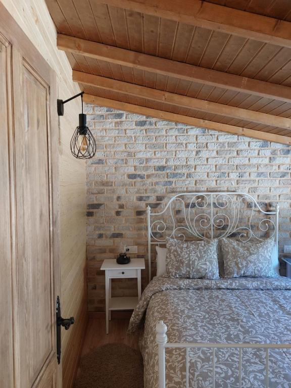 - une chambre avec un lit blanc et un mur en briques dans l'établissement CON ENCANTO, à Cabezuela del Valle