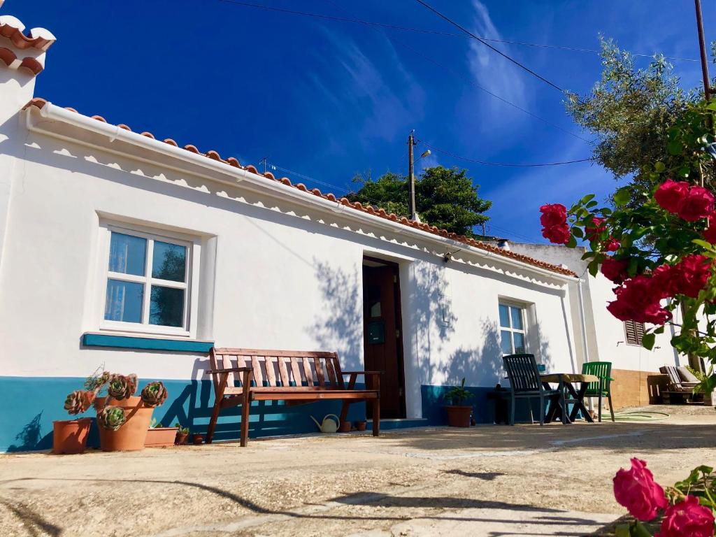 une maison blanche avec un banc en bois devant elle dans l'établissement Casa Anneli - relaxing under the olive tree, à Aljezur