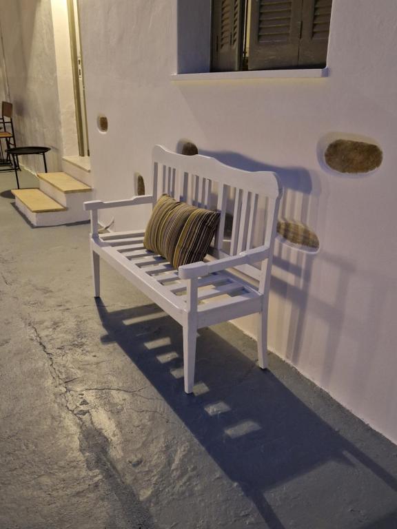 una panchina bianca seduta di fronte a un edificio di The Garden House a Città di Tinos