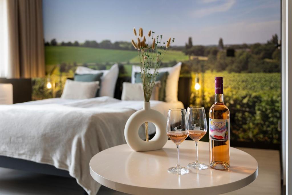 zwei Gläser Wein auf einem Tisch neben einem Bett in der Unterkunft Dormio Wijnhotel Valkenburg in Valkenburg