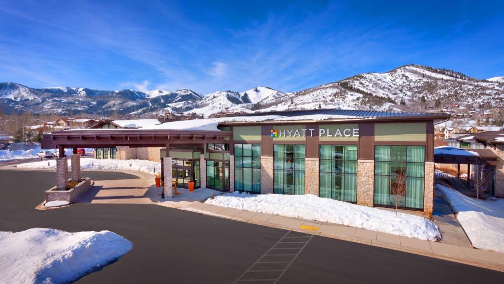 a building with snow covered mountains in the background at Hyatt Place Park City in Park City