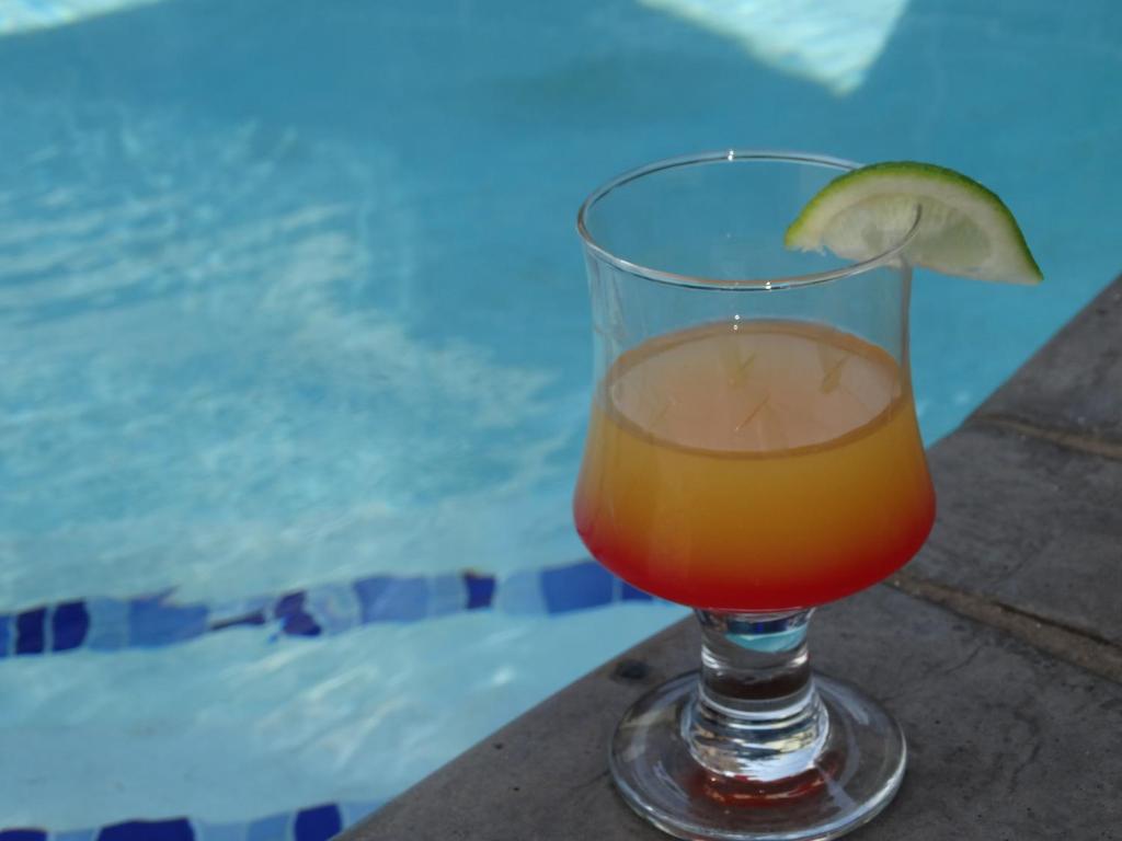 a drink in a glass sitting next to a pool at Isle La Breeze Guest House in Witbank