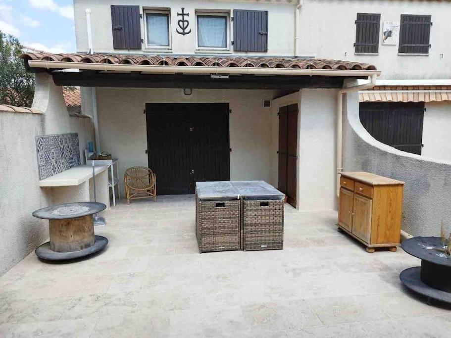 une terrasse avec une table et une maison dans l'établissement Maison climatisée avec piscine, terrasse et place de parking privative, à Saintes-Maries-de-la-Mer
