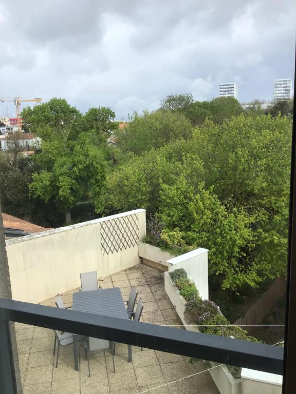 - un balcon avec une table, des chaises et des arbres dans l'établissement Le Beltremieux, à La Rochelle
