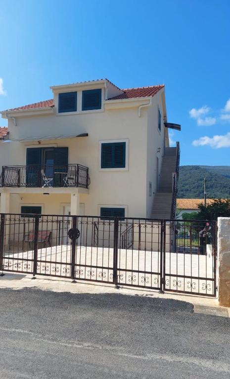 a white house with a black fence in front of it at Apartmani Elisa in Stari Grad