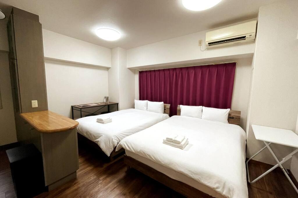 - une chambre d'hôtel avec 2 lits et un rideau rouge dans l'établissement PlusTom Stay-SHIMANOUCHI-, à Osaka