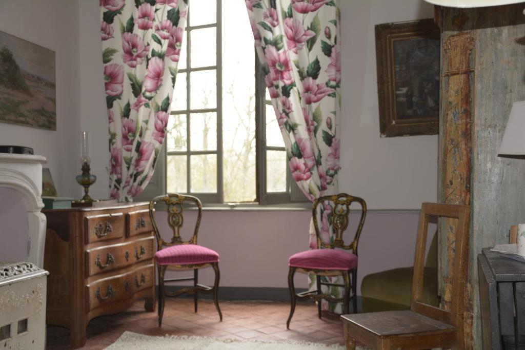 Habitación con 2 sillas y una ventana con cortinas rosas. en Le Perchoir, en Cosne-Cours-sur-Loire