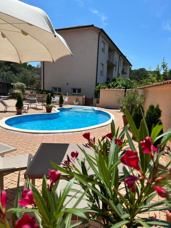 ein Pool mit Sonnenschirm und ein paar Blumen in der Unterkunft Apartments Villa Julia in Pakoštane