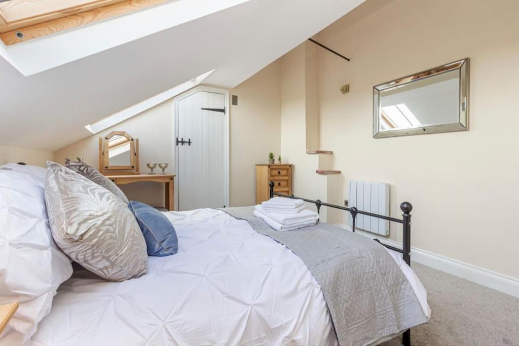 a bedroom with a white bed and a mirror at Cosy 2 bed with parking and garden in Cawston