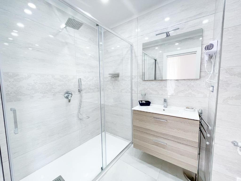 um banheiro branco com chuveiro e pia em La Canzonetta Affittacamere em Nápoles