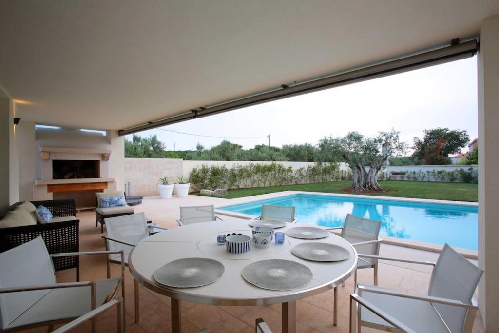 a dining room with a table and chairs and a pool at Luxury villa Lara with private pool in Banjole