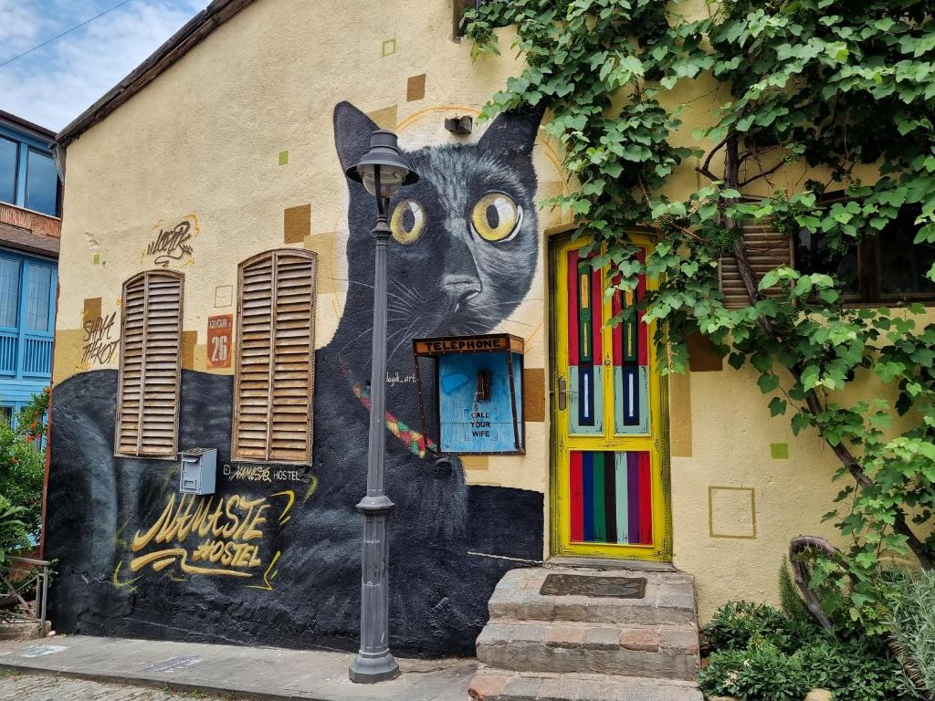 un mural de un gato al lado de un edificio en Namaste Hostel en Tiflis
