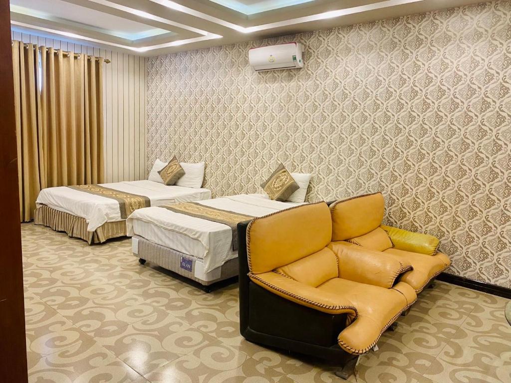 une chambre d'hôtel avec deux lits et un canapé dans l'établissement Holiday Hotel, à Hai Phong