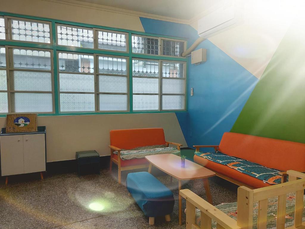 a room with a couch and a table and windows at 老宅小巷6人包棟民宿 in Taitung City