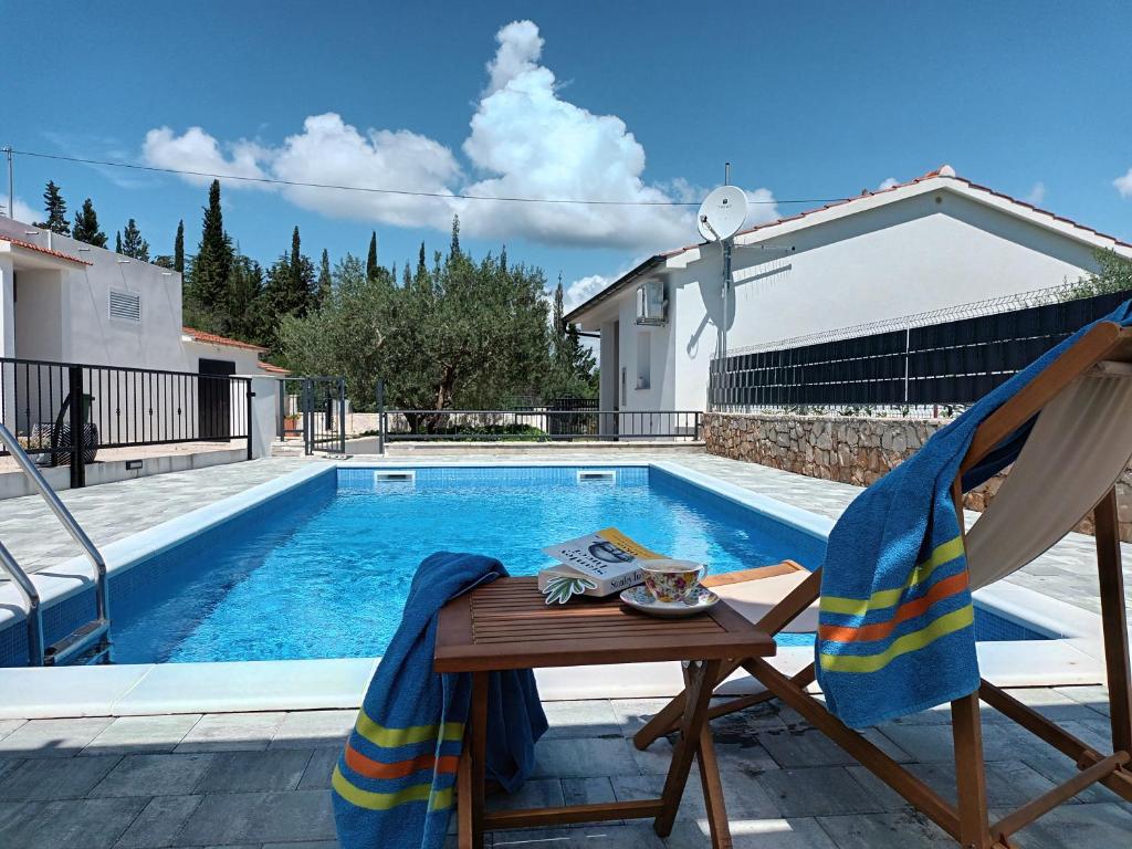 - une table et une chaise à côté de la piscine dans l'établissement Holiday home Mala, à Šibenik