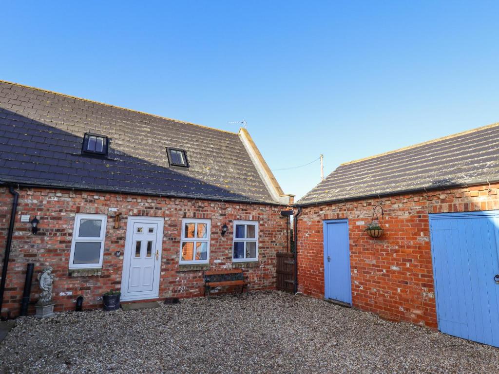 a brick house with white doors and a courtyard at Saddle Rack Cottage in Louth