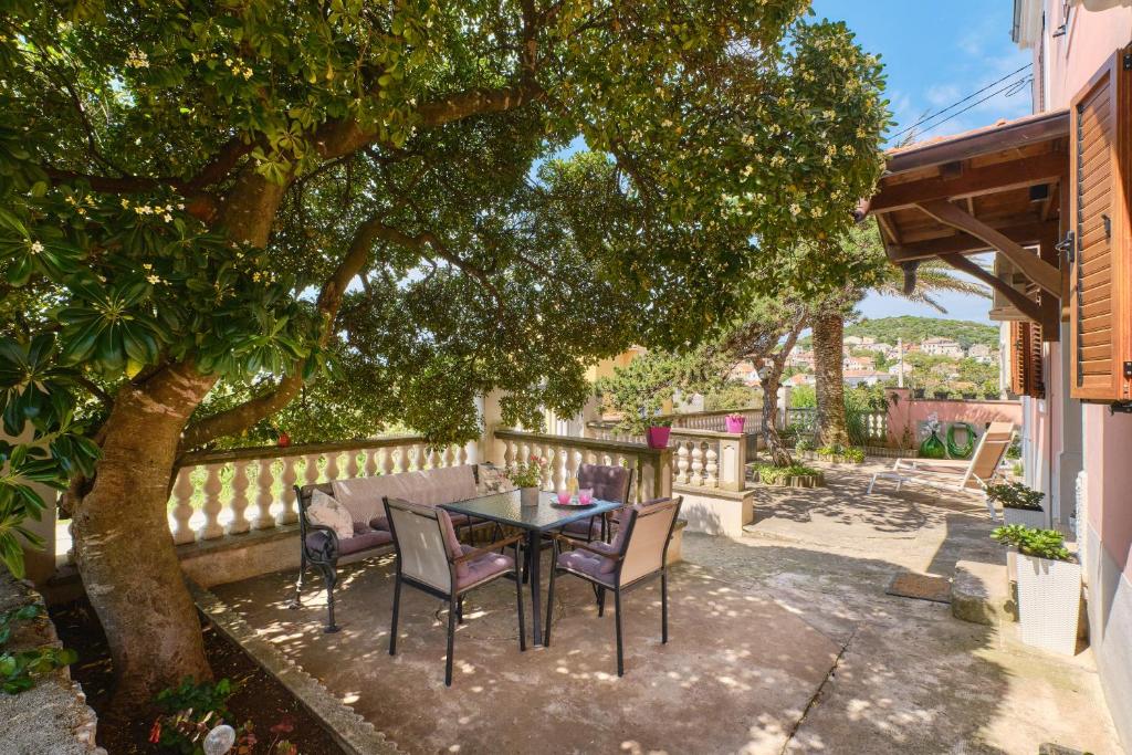 Bella Vista في Čunski: فناء فيه طاولة وكراسي تحت شجرة