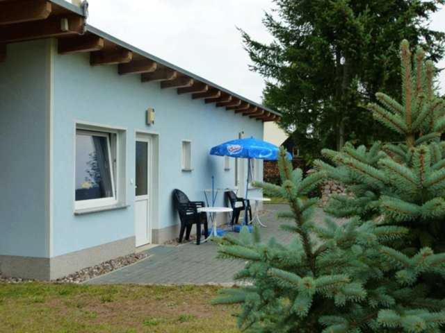 a blue house with a table and an umbrella at Ferienunterkuenfte Feldmann in Korswandt