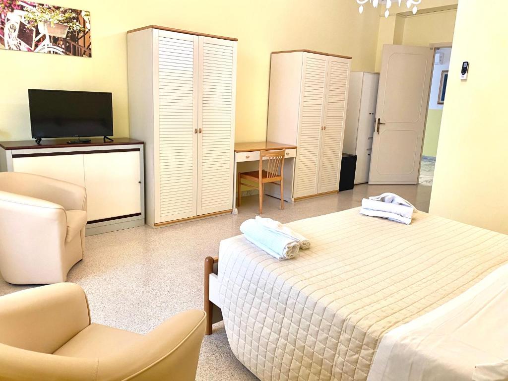 een slaapkamer met een bed, een stoel en een televisie bij OSTELLO MADRE SANTINA in Lecce