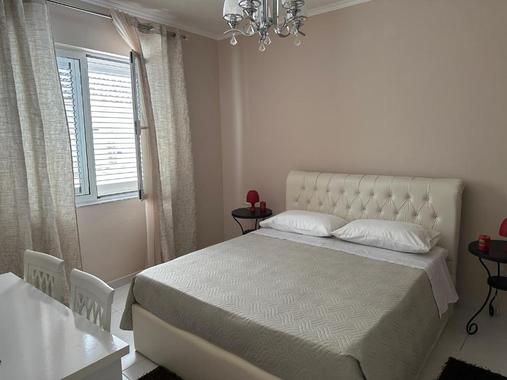 a white bedroom with a bed and a chandelier at Andrea House in Berat