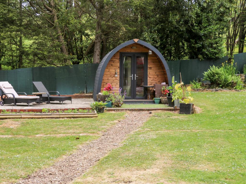 a small cabin in a garden with a fence at The South Lodge Retreat in East Grinstead