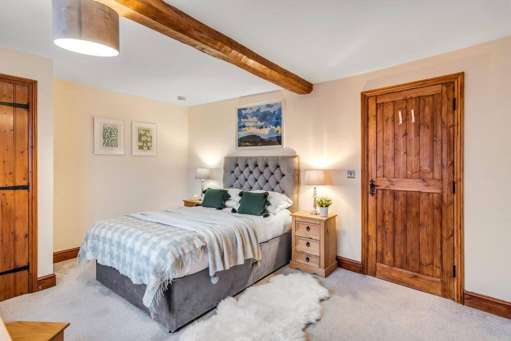a bedroom with a bed and a wooden door at The Woodrow Cottage in Cawston
