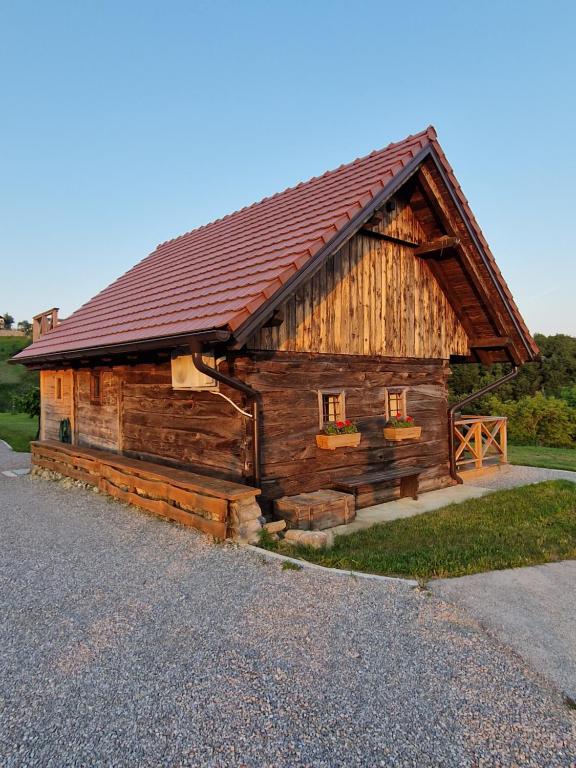 une cabane en rondins avec un toit rouge sur le côté dans l'établissement Vineyard cottage Vinska grajska kašča, à Mirna