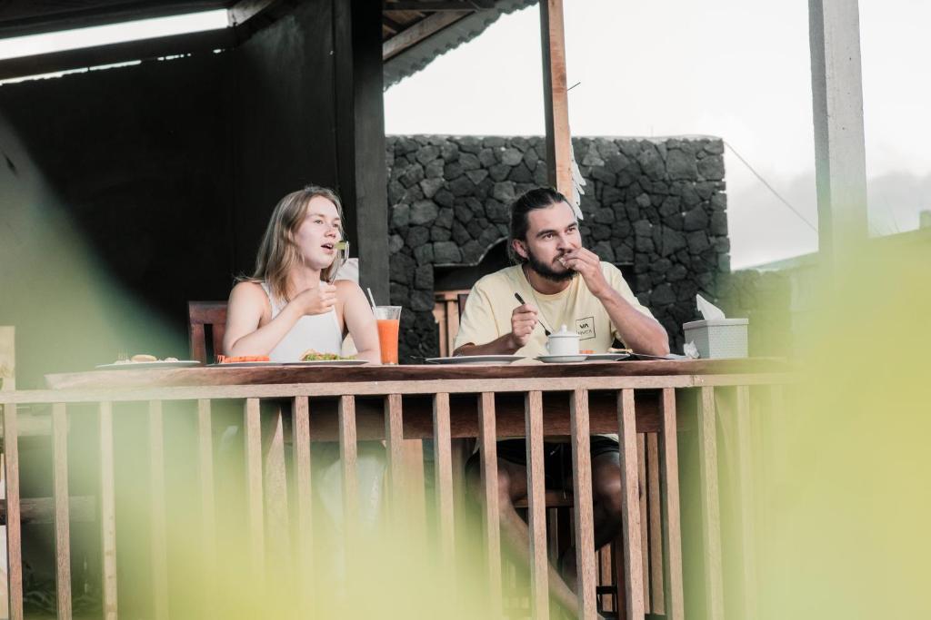 um homem e uma mulher sentados à mesa em Batur cottage em Kubupenlokan