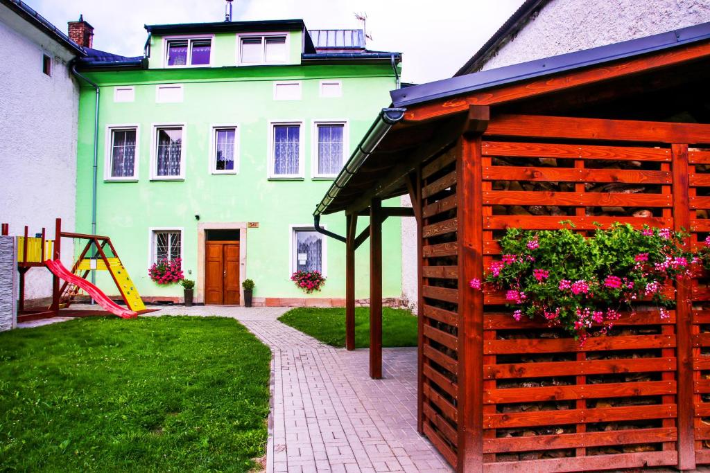 a green house with a wooden fence and a playground at Alexandra in Svoboda nad Úpou