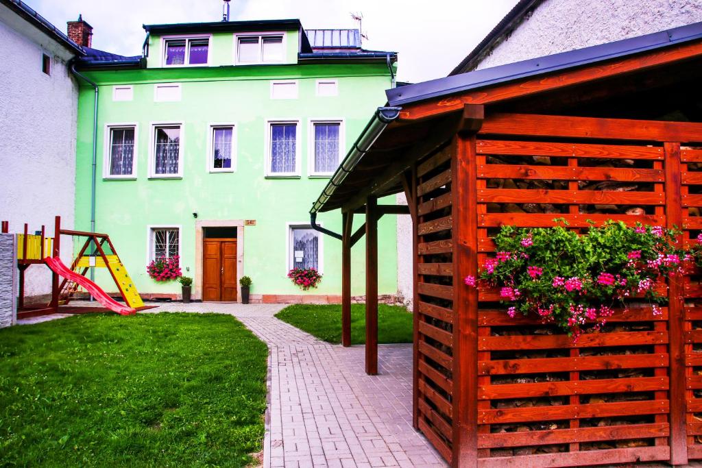 ein grünes Haus mit einem Holzzaun und einem Spielplatz in der Unterkunft Alexandra in Svoboda nad Úpou