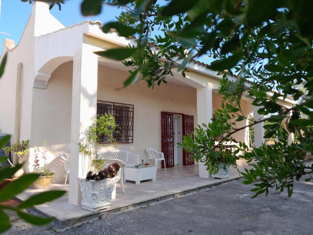 une maison blanche avec une terrasse couverte et des chaises dans l'établissement Casa in campagna ⋅ ForiMìa, à San Vito dei Normanni